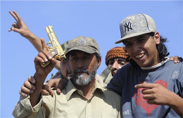 Des combattants du CNT brandissent un pistolet plaqué or qui appartenait à Kadhafi, à Syrte ( PHOTO  ) 